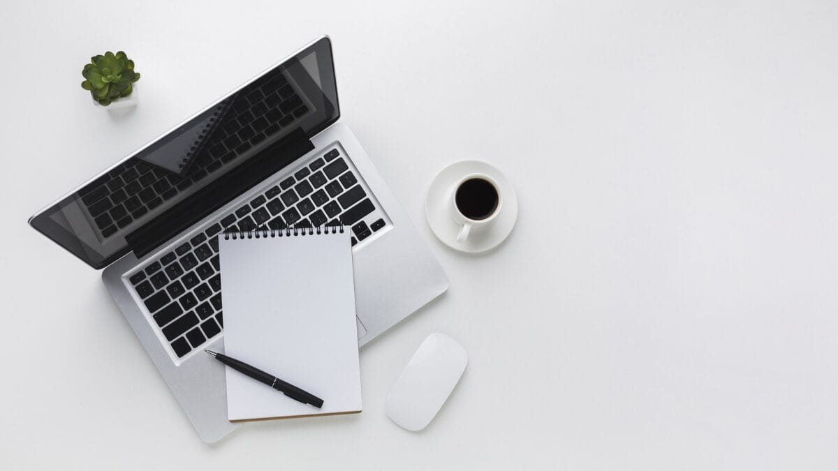 Laptop, anteckningsblock och en kopp kaffe på ett vitt bord | NTI-skolan