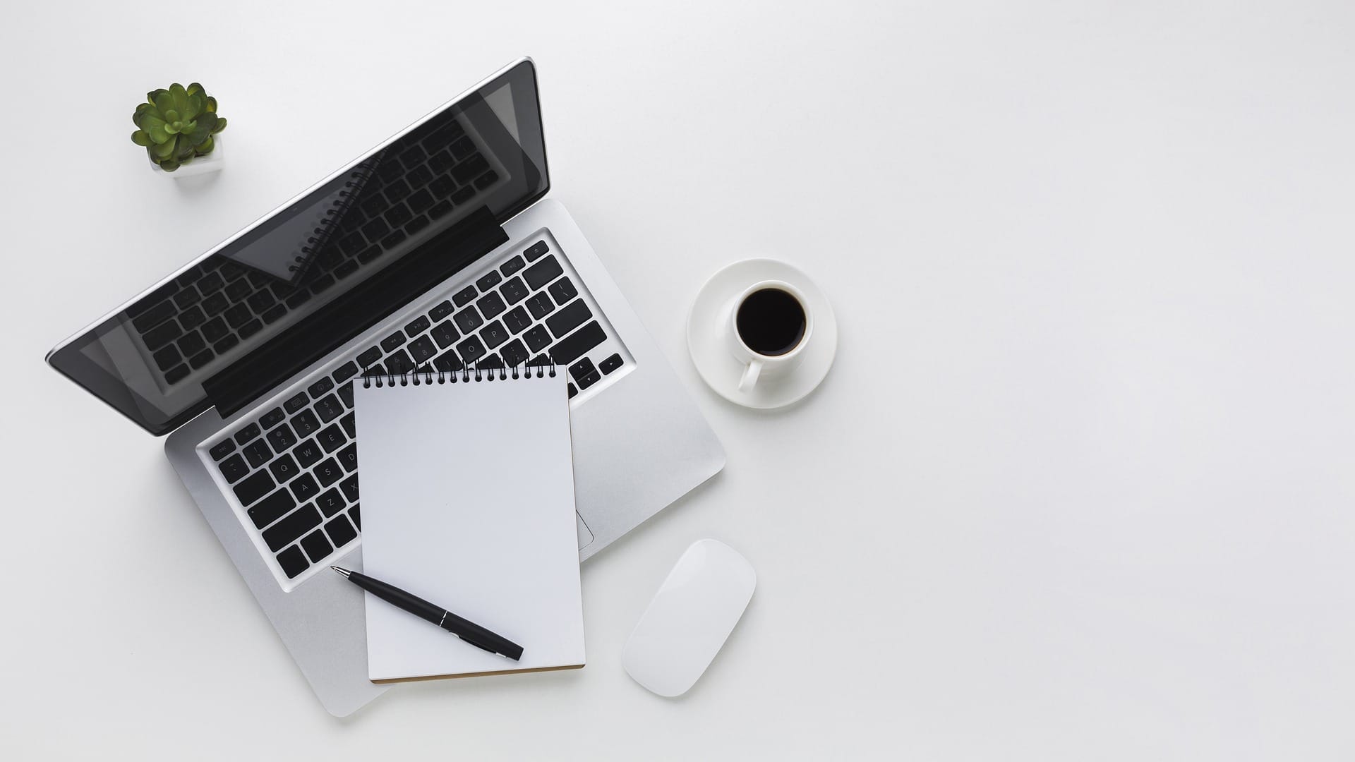 Laptop, anteckningsblock och en kopp kaffe på ett vitt bord | NTI-skolan